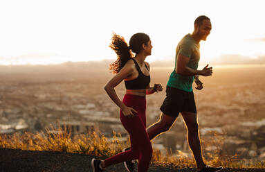 Athleten laufen auf der Straße am frühen Morgen. Fitness-Mann und Frau sprinten auf der Straße. - JLPSF14646