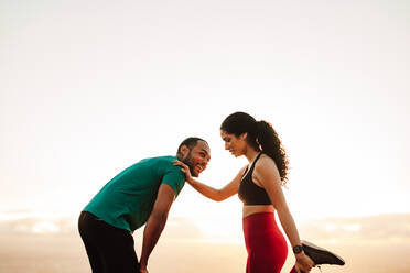 Athletic man and woman standing outdoors relaxing after workout. Cheerful fitness couple exercising standing outdoors. - JLPSF14648