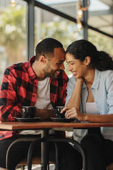 Liebevolles Paar, das eine tolle Zeit zusammen bei einem Date im Café hat. Afrikanischer Mann und Frau lächelnd im Café. - JLPSF14658