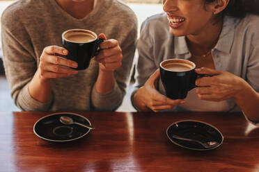 Abgeschnittene Aufnahme von zwei Freundinnen, die zusammen in einem Café Kaffee trinken. - JLPSF14671