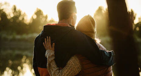 Rear view of couple standing together by the lake. Man and woman in warm clothing looking at a view. - JLPSF14686