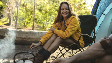 Beautiful woman sitting at campfire and looking at her man. Couple on camping sitting outside the tent. - JLPSF14699