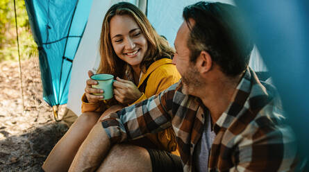Reifes Paar beim Wochenend-Camping: Mann und Frau sitzen im Zelt, schauen sich an und lächeln. - JLPSF14700