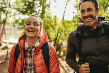 Cheerful couple walking with backpack to their camping site. Mature couple on a camping trip on a weekend. - JLPSF14713