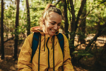 Frau mit Rucksack im Wald stehend und lächelnd, Camperin lächelnd. - JLPSF14719