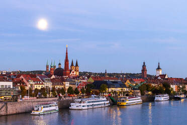 Germany, Bavaria, Wurzburg, Moon glowing over river Main with Wurzburg Cathedral and Marienkapelle in background - NDF01543