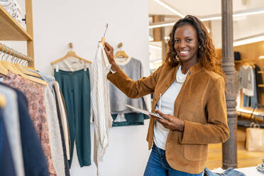 Happy manger arranging clothes in store - DLTSF03283