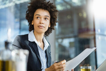 Contemplative businesswoman with document at office - DIGF19067