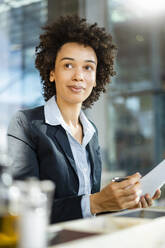 Businesswoman with curly hair holding document - DIGF19068