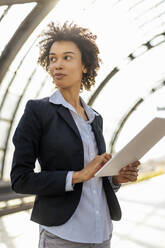 Businesswoman wearing blazer holding tablet PC at railroad station - DIGF19073