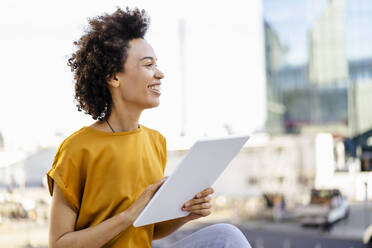 Happy businesswoman with curly hair holding tablet PC - DIGF19079