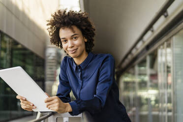 Smiling businesswoman with tablet PC leaning on railing - DIGF19113