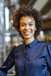 Happy businesswoman with curly hair wearing blue shirt - DIGF19122