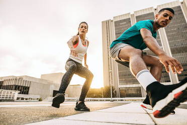 Ein fitter Mann und eine fitte Frau trainieren gemeinsam im Freien in der Stadt. Ein Paar bei Trainingsübungen in der Stadt. - JLPSF14744