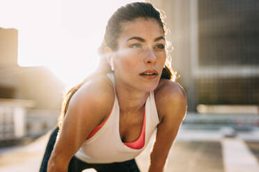 Läuferin, die nach einem Lauf in der Stadt gebückt steht und Luft holt. Sportliche Frau, die nach einem Lauf eine Pause macht. - JLPSF14751