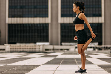 Fitness woman stretching outdoors. Sporty female doing warm up exercise in morning in the city. - JLPSF14780