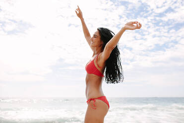 Junge Frau im Bikini, die am Strand tanzt. Kaukasisches weibliches Modell am Meeresufer, das sich amüsiert. - JLPSF14860