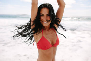 Fröhliche junge Frau im Bikini genießt am Strand. Kaukasische Frau im Badeanzug tanzt am Meeresufer. - JLPSF14867