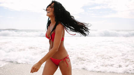 Lachende Frau, die aus dem Meer kommt, Frau im Bikini, die lächelnd am Strand spazieren geht. - JLPSF14868