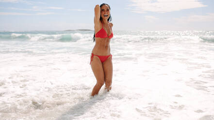 Woman in bikini having fun in the beach. Cheerful young female in swimsuit enjoying her summer holidays at the beach. - JLPSF14874