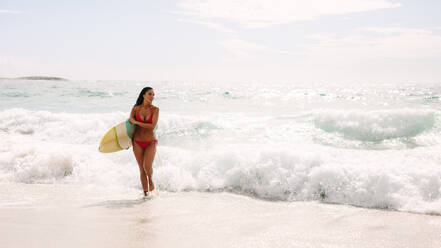 Junge Frau mit Surfbrett, die aus dem Meer kommt. Schöne kaukasische Frau mit Surfbrett, die aus dem Ozean kommt. - JLPSF14879