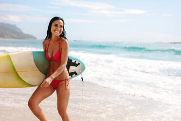 Schöne Frau, die mit einem Surfbrett aus dem Meer steigt. Weibliche Surferin am Meeresufer. - JLPSF14880
