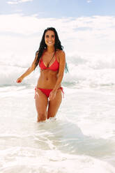 Happy young woman in bikini walking out of the sea. Female having fun on the beach. - JLPSF14896