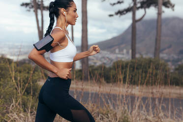 Sportlerin, die frühmorgens auf einer Landstraße läuft. Fitness-Frau, die im Freien sprintet. - JLPSF14924