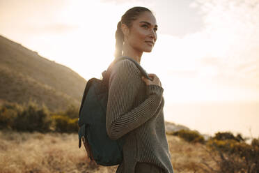 Woman walking on a hill path with a backpack. Woman wearing sweater and backpack on hiking. - JLPSF14947