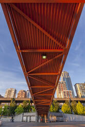 Red bridge seen from below with high rise buildings and contruction sites in background. - MINF16573