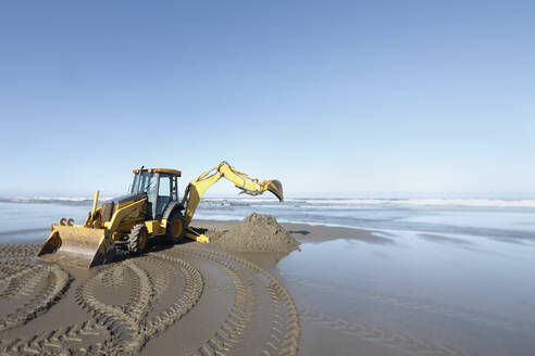 Ein Bagger, ein Bagger mit großer Schaufel bei der Arbeit auf dem weichen Sand am Ufer des Wassers. - MINF16581