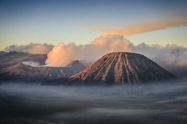 Der Vulkan Mount Bromo, ein Soma-Vulkan und Teil des Tengger-Gebirges, dessen Kegel sich über den Nebel in der Landschaft erhebt. - MINF16590