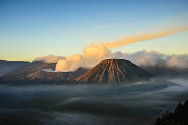 Der Vulkan Mount Bromo, ein Soma-Vulkan und Teil des Tengger-Gebirges, dessen Kegel sich über den Nebel in der Landschaft erhebt. - MINF16591