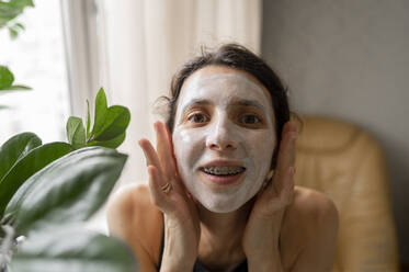 Woman with braces applying facial mask at home - ANAF00246