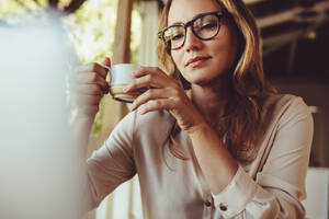 Frau sitzt im Café mit einer Tasse Kaffee und schaut auf den Laptop. Geschäftsfrau trinkt einen Kaffee und arbeitet in einem Café. - JLPSF14993