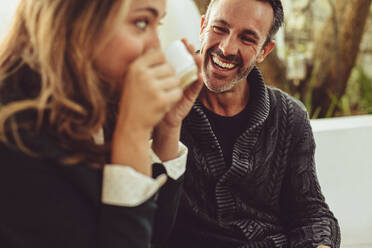 Smiling man looking at his girlfriend drinking coffee. Couple sitting at coffee shop. - JLPSF15008