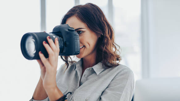 Frau mit Spiegelreflexkamera beim Fotografieren in Innenräumen. Kaukasische Fotografin mit Kamera beim Fotografieren. - JLPSF15041