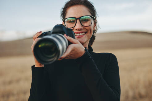 Schöne Frau mit einer Kamera nimmt Bilder im Freien. Weibliche Fotografin arbeitet im Freien Lage. - JLPSF15061