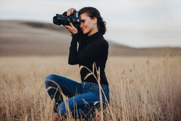 Junge Frau mit dslr-Kamera für die Aufnahme von Bildern im Freien. Weibliche professionelle Fotografin, die Bilder mit einer DSLR-Kamera. - JLPSF15072
