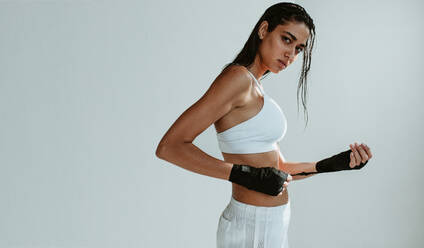 Gesunde weibliche Boxerin mit Boxhandschuhen. Muskulöse Frau, die sich auf ein Boxtraining vor weißem Hintergrund vorbereitet. - JLPSF15131
