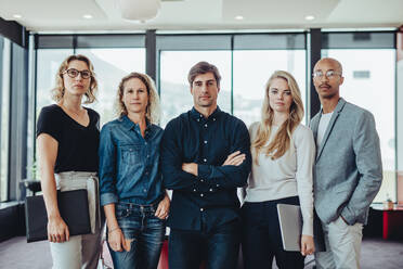 Porträt eines Geschäftsteams, das in einem Büro zusammensteht. Gruppe von Männern und Frauen, die in die Kamera schauen, in einem Sitzungssaal. - JLPSF15174