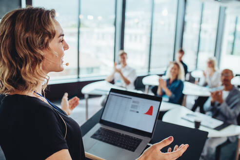 Geschäftsfrau, die von einem Podium aus zu Geschäftsleuten spricht. Weibliche Führungskraft, die auf einer Konferenz zu einer Gruppe von Fachleuten spricht. - JLPSF15204