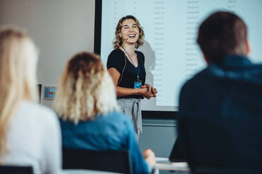 Businesswoman standing at projector screen and smiling during a presentation. Successful female entrepreneur delivering a speech at conference. - JLPSF15205