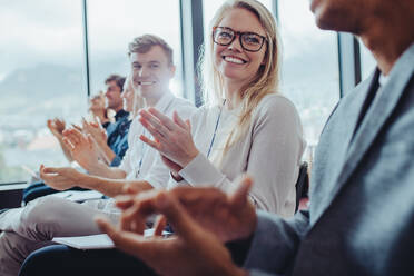 Group of businesspeople sitting at seminar clapping hands. Businessmen and businesswomen applauding after a successful presentation at a conference. - JLPSF15212