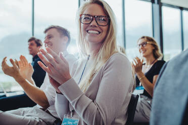 Businesspeople sitting at seminar clapping hands. Businessmen and businesswomen applauding after a successful presentation. - JLPSF15215