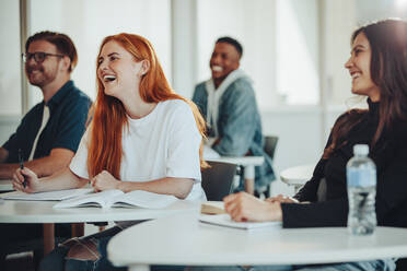 Eine Gruppe multiethnischer Studenten sitzt in der Klasse und lächelt während der Vorlesung. Lachende Highschool-Schüler im Klassenzimmer. - JLPSF15224