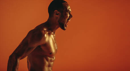 Seitenansicht Porträt eines muskulösen Mannes, der aggressiv schreit. Ausgeschnittene Aufnahme eines afrikanischen Mannes mit nacktem Oberkörper, der schreit. - JLPSF15273