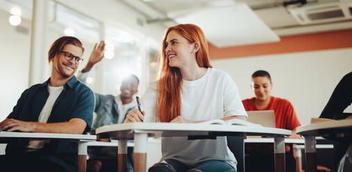 Männliche und weibliche Studenten unterhalten sich während der Vorlesung im Klassenzimmer. Studenten lächeln und diskutieren in der Vorlesung. - JLPSF15368