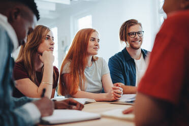 Eine Gruppe von männlichen und weiblichen Studenten sitzt um einen Tisch herum und lernt. Klassenkameraden in der High School, die gemeinsam lernen. - JLPSF15383