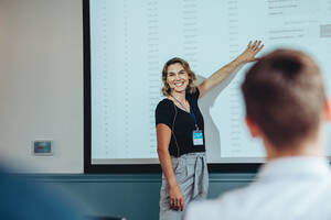 Smiling businesswoman giving a presentation to her colleagues during a conference. Female speaking showing some financial figures during a presentation. - JLPSF15395